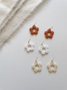 four pairs of earrings on top of a white table next to a towel and cloth