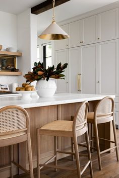 a kitchen with white cabinets and wooden stools next to an island in the middle