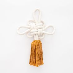 an orange tassel hanging from a white rope on top of a white wall or floor