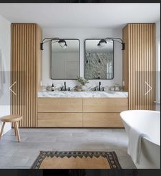 a large bathroom with two sinks, mirrors and a rug on the floor in front of it