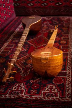 two wooden guitars sitting on top of a rug