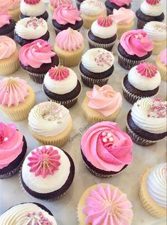 there are many cupcakes with pink and white frosting