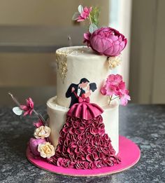 a wedding cake decorated with flowers and a bride and groom topper on a pink plate