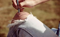 a person holding a pencil in their left hand and writing on the back of someone's leg