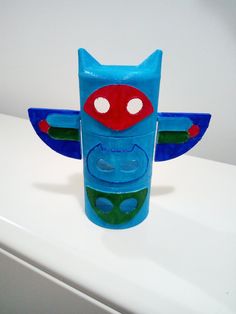 a blue toy with red and green eyes on top of a white counter next to a wall