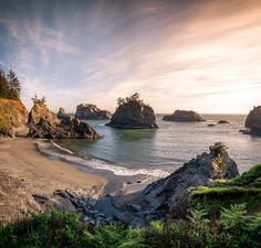 the beach is surrounded by large rocks and trees