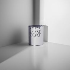 a can of paint sitting on top of a white counter next to a wall with the words coat coat painted on it