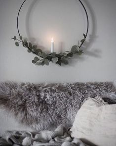 a candle is lit in the middle of a circular wreath on a wall above a bed