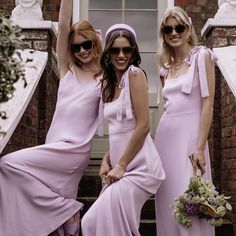 three beautiful women in long dresses standing next to each other on steps with their hands up