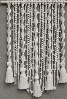 a wall hanging made out of rope with tassels and beads on the side