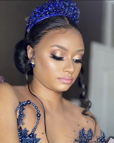 a woman with blue makeup is wearing a tiara and looking down at her cell phone