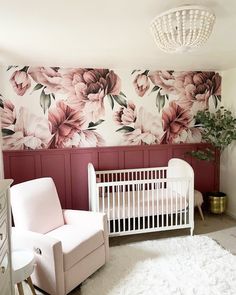 a baby's room decorated in pink and white with flowers on the wall behind it