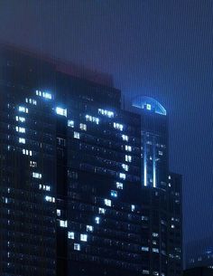 the city skyline is lit up at night, with skyscrapers in the foreground