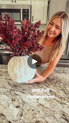 a woman kneeling down in front of a counter top with a vase filled with flowers