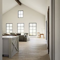 an open concept kitchen and living room with white walls, wood flooring and vaulted ceiling