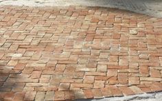 a dog laying on the ground next to a brick walkway