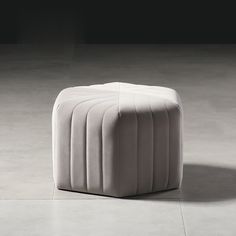 a white ottoman sitting on top of a floor next to a black and white wall