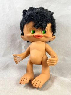 a troll doll with black hair and green eyes