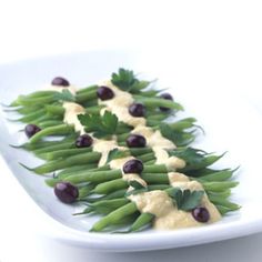 green beans and olives are arranged on a white plate