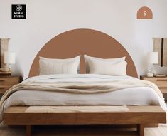 there is a bed with two pillows on top of it and a brown circle wall decal behind it