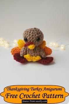 a small crocheted turkey sitting on top of a white table next to a string of lights