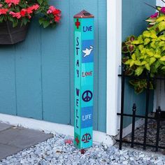 a pole that has some writing on it in front of a building with flowers and potted plants