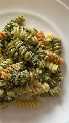 a white plate topped with pasta and broccoli covered in pesto cheese sauce