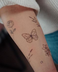 a woman's arm with a butterfly and flower tattoo on the left side of her arm