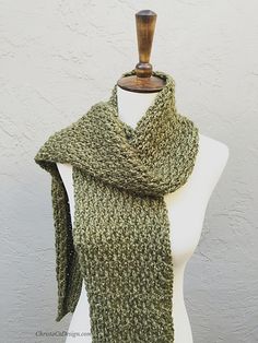 a green knitted scarf sitting on top of a mannequin