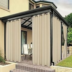 a patio covered in curtains next to a house