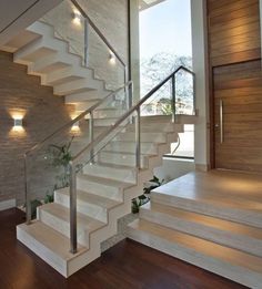 there is a stair case with lights on the wall and wood floors in this house