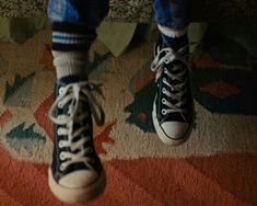 a person standing on top of a rug with their feet in the air and wearing converse shoes