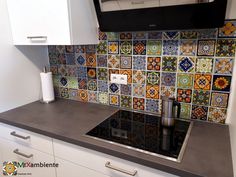 a kitchen with white cabinets and colorful tiles on the backsplash, along with stainless steel counter tops