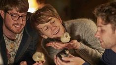 three men are laughing and eating food together