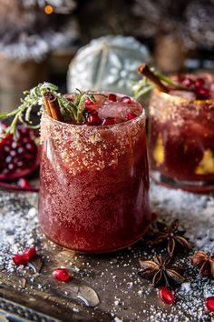 two glasses filled with ice and garnish on top of a wooden table covered in snow