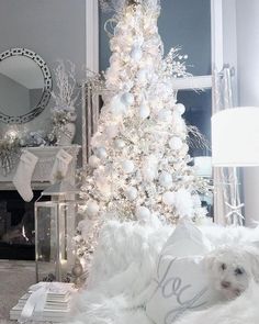 a white christmas tree in the corner of a living room with a dog laying next to it