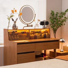 a bedroom with a bed, desk and mirror on it's side table in front of a window