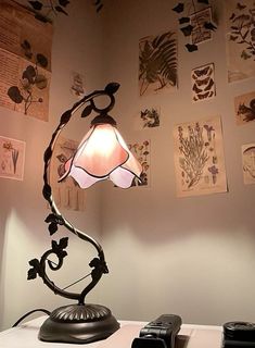 a lamp sitting on top of a table next to a cell phone and pictures hanging on the wall