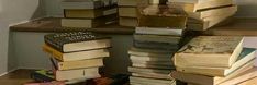 a pile of books sitting on top of a wooden shelf