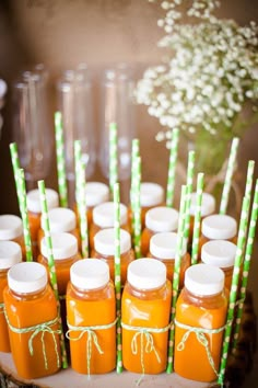 there are many orange juices with green straws in the bottles on the table