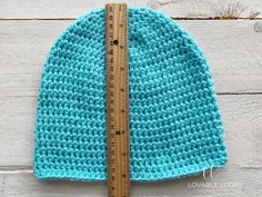 a blue crocheted hat with a ruler next to it