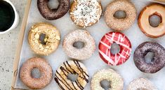 a box filled with lots of different flavored doughnuts next to a cup of coffee