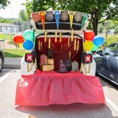 the back of a vehicle with balloons and decorations on it's trunk, parked in a parking lot