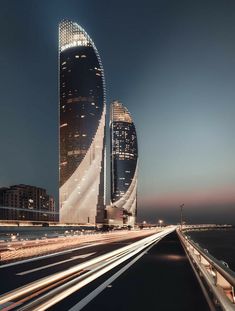 a very tall building sitting on the side of a road next to some buildings at night