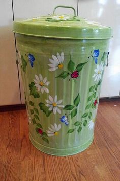 a green trash can sitting on top of a wooden floor