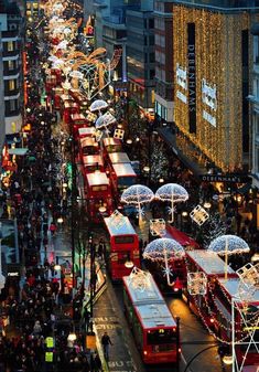 a busy city street filled with lots of traffic and christmas lights on the side of buildings