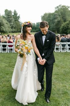 a bride and groom walking down the aisle at their outdoor wedding in an open field