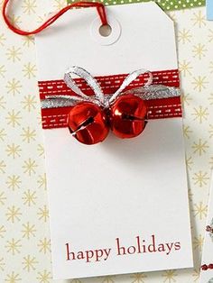 a christmas gift tag with a red bow and silver glittered bell attached to it