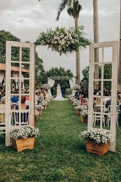 an outdoor ceremony setup with white chairs and flowers on them, surrounded by palm trees