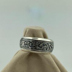 a silver ring with filigrees on it sitting on top of a cloth